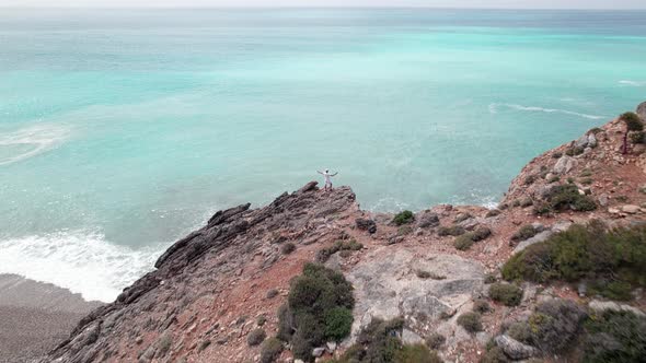 Man Stands on a Cliff Above Sea