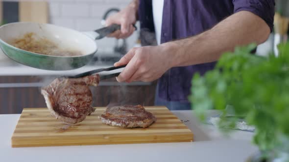 Man putting Cooked Juicy Steak on Cutting Board