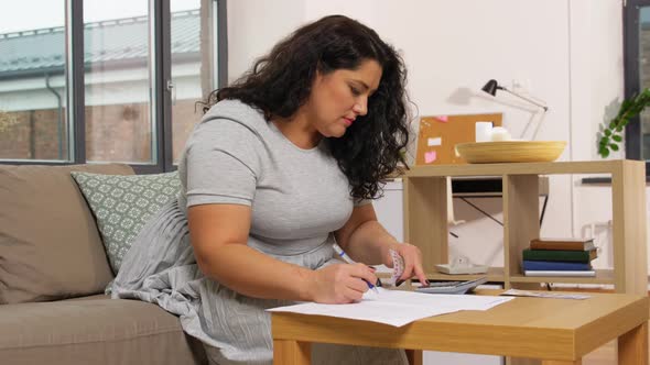 Woman with Money, Papers and Calculator at Home