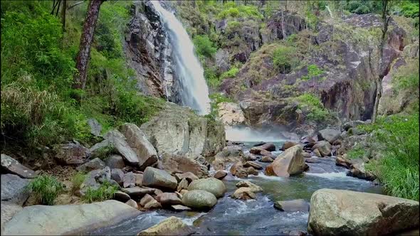 Drone Flies From Waterfall To Mountain River Among Rocks
