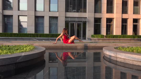 Beautiful Young Girl Dancing on the Street of a Modern City and Is Reflected in the Water. She Is