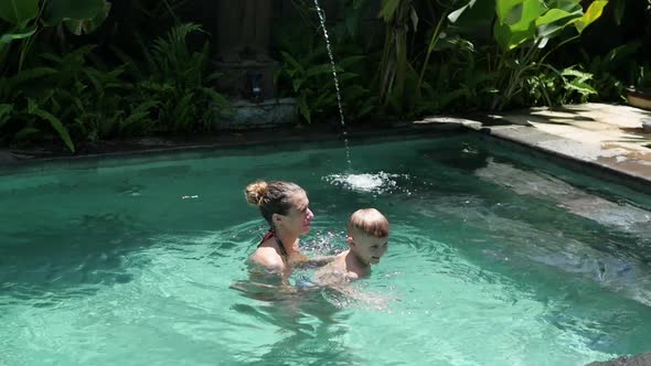 Little Boy Swims with Mom in the Pool on Vacation in Asia, Baby Swimming. Mom and Son Swim in the