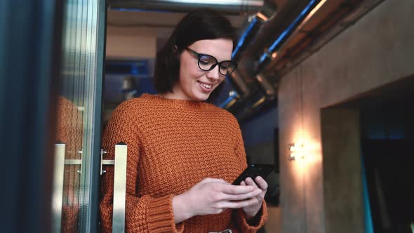 Positive red haired woman texting by mobile