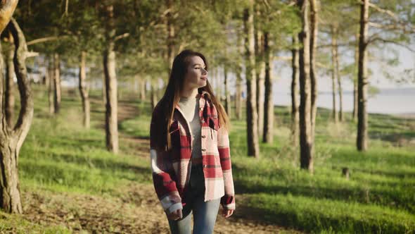 Beautiful Young Hipster Woman in a Shirt Walking Through a Picturesque Pine Forest