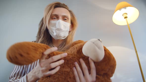 Bottom View of Young Dad Wearing Safety Mask and Holding Stuffed Animal Playing with Baby