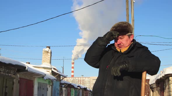 A Closeup of a Man in Warm Clothes is Leaning on a Shovel He is Resting