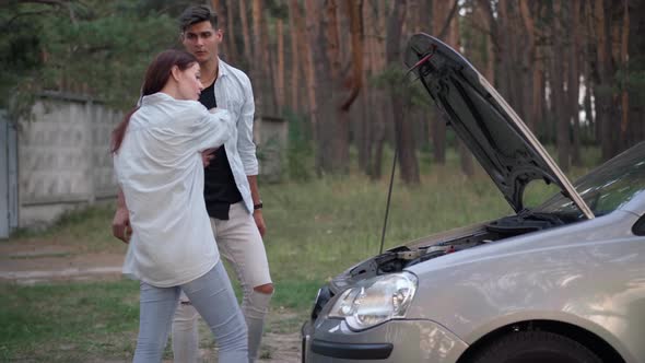 Slim Woman Rolling Up Sleeves Walking to Open Car Hood Pushing Away Man