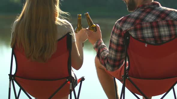 Happy Woman and Man Sitting on Folding Chairs Near Lake