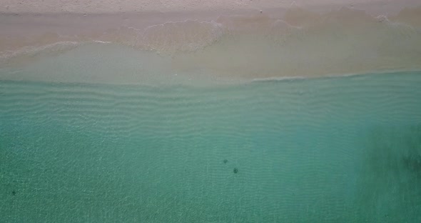 Wide angle fly over travel shot of a white paradise beach and blue sea background in vibrant 4K