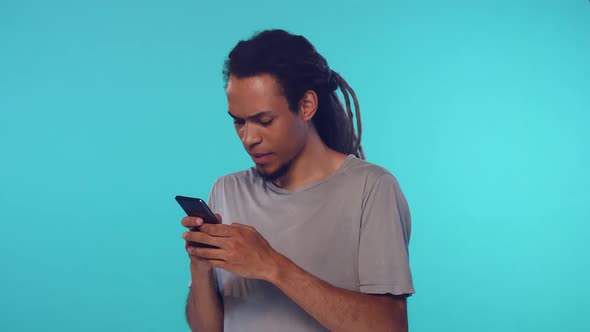 Shocked Stylish African American Guy Nervously Typing Text on His Smart Phone