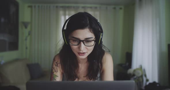 Portrait of Young Woman Wearing Headset and Glasses Speaking in Group Chat During Remote Work at