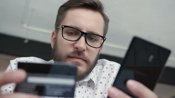 Man Using Online Banking with Smart Phone and Card