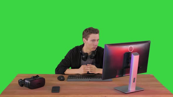 Serious Gamer Sitting at Computer Watching a Game on a Green Screen, Chroma Key