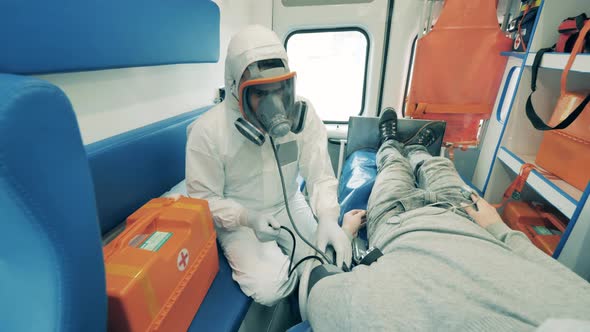 Paramedic in a Hazmat Suit is Measuring Patient's Pressure