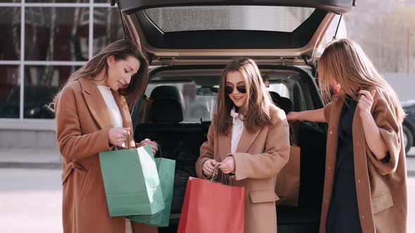 Attractive Girls Have Shopped and Checking Purchases at the Car Back