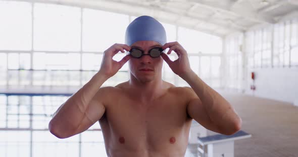 Swimmer taking off his pool goggles and looking at camera