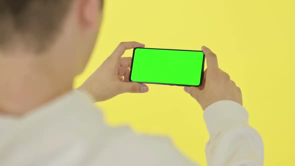 Watching Horizontal Smartphone with Green Screen Yellow Background