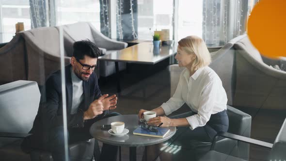 Business Partners Man and Woman Sharing News Talking in Cafe Over Coffee