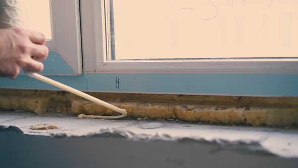 Builder Applies Spray Foam Insulation on Windowsill Closeup