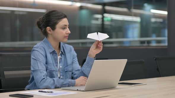 Indian Woman Flying Paper Plane While Working on Laptop