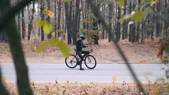 Cyclist in Black Helmet Is Typing Message, Putting Phone in His Pocket and Starts His Training Ride