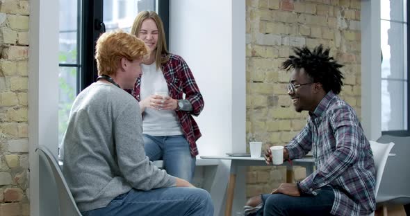 Positive African American and Caucasian Coworkers Laughing During Break in Office. Cheerful Happy