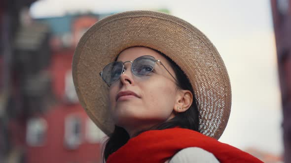 Young woman in a hat and sunglasses in a summer city