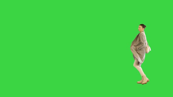 Young Woman in Stylish Clothes Walks Dancing Slightly on a Green Screen Chroma Key