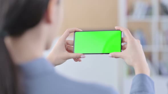Latin Woman Looking at Smartphone with Green Chroma Key Screen