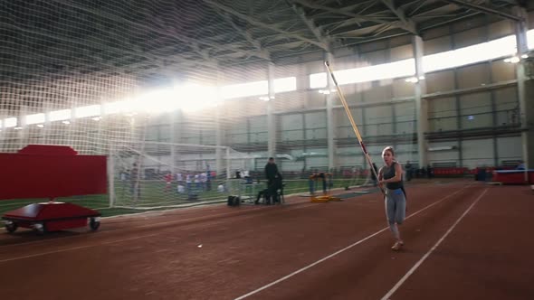 Pole Vault Training - a Young Woman with Ponytail Running Up and Jumping Over the Bar - Touches the