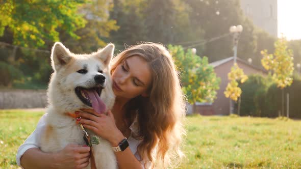 Young woman walking her cute Akita Inu dog in park on sunny day. Lovely pet