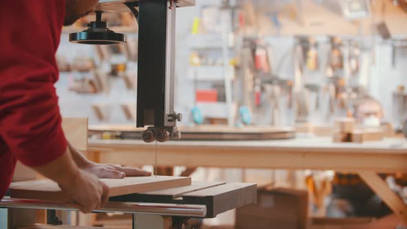 Carpentry Indoors - a Man Woodworker Cuts Off a Layout of the Detail From a Wooden Block