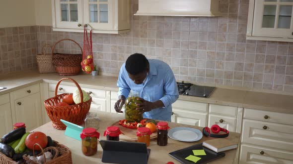 Live Camera Zoom in to Positive African American Man Smelling Canned Cucumber Opening Bottle in