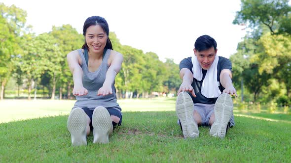 Asian male and female couple Exercise in the outdoor park in the morning.