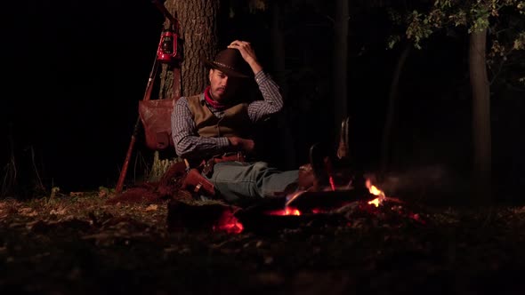 Cowboy Near the Fire in the Forest at Night