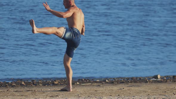 Sports Exercises Outdoors  Young Fit Man Performing Fighting Movements on the Beach