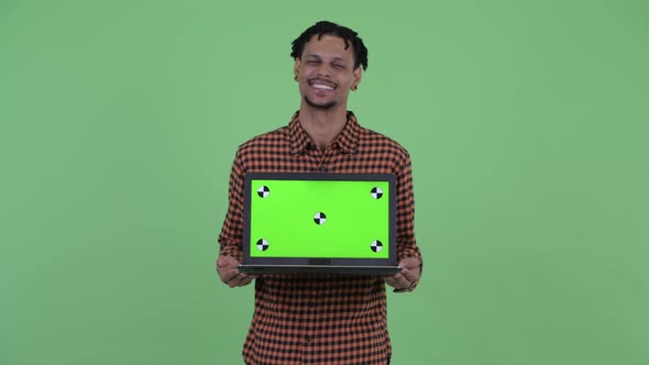 Happy Young Handsome African Man Thinking While Showing Laptop