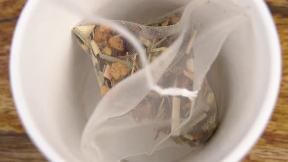 Herbal flower fruit tea in a micro plastic bag is placed in a white teacup