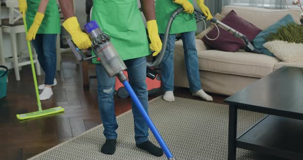 Multiracial Cleaning Team Doing wet Cleaning with Vacuums and Mop in Customer House