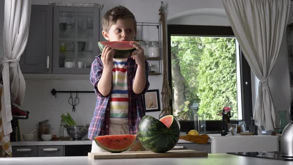 Little kid eating watermelon in kitchen