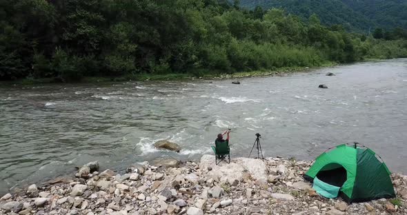 On the Banks of a Mountain River a Fisherman Catches Fish Pitched a Green Tent