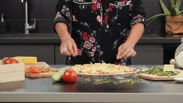 Woman preparing tasty pizza at home. Process of making pizza.