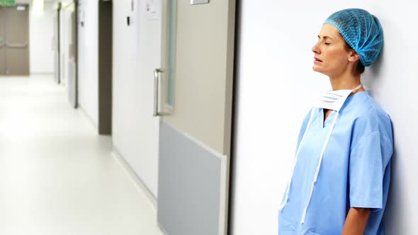 Sad surgeon leaning on wall in corridor