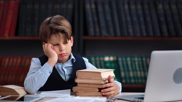 Tired Frustrated Male Kid Schooler Sleeping with Stack of Textbook on Table at Public Library