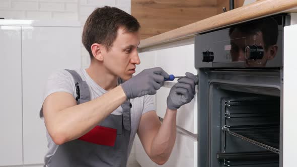 Skilled Employee Twists Screw on Broken Oven Repairing