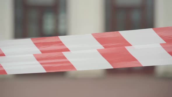 Close-up of Red and White Barricade Tape with Blurred Urban Building at the Background. City