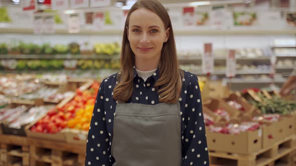 Portrait of a Female Worker in an Apron Against a Background of Fruits a Young Woman Crosses Her