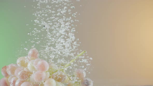 Grapes fall into water on isolated background