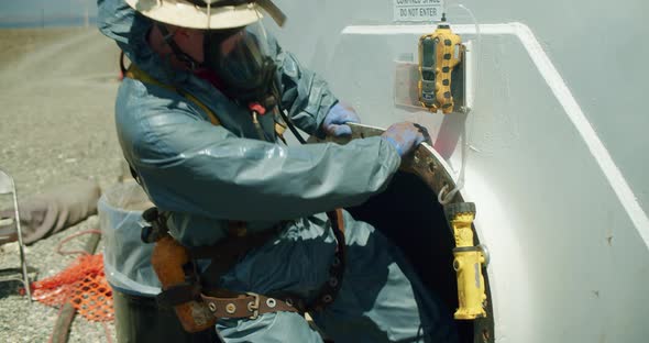 Man in Full Chemical PPE and Supplied Air Entering into Aboveground Storage Tank