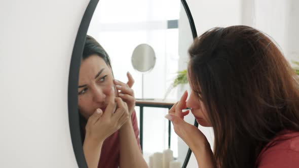 Slow Motion of Young Woman Touching Face Looking for Imperfections on Skin in Bathroom